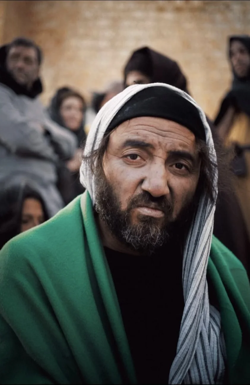 Cyrus Esfandiari as a character in a green cloak