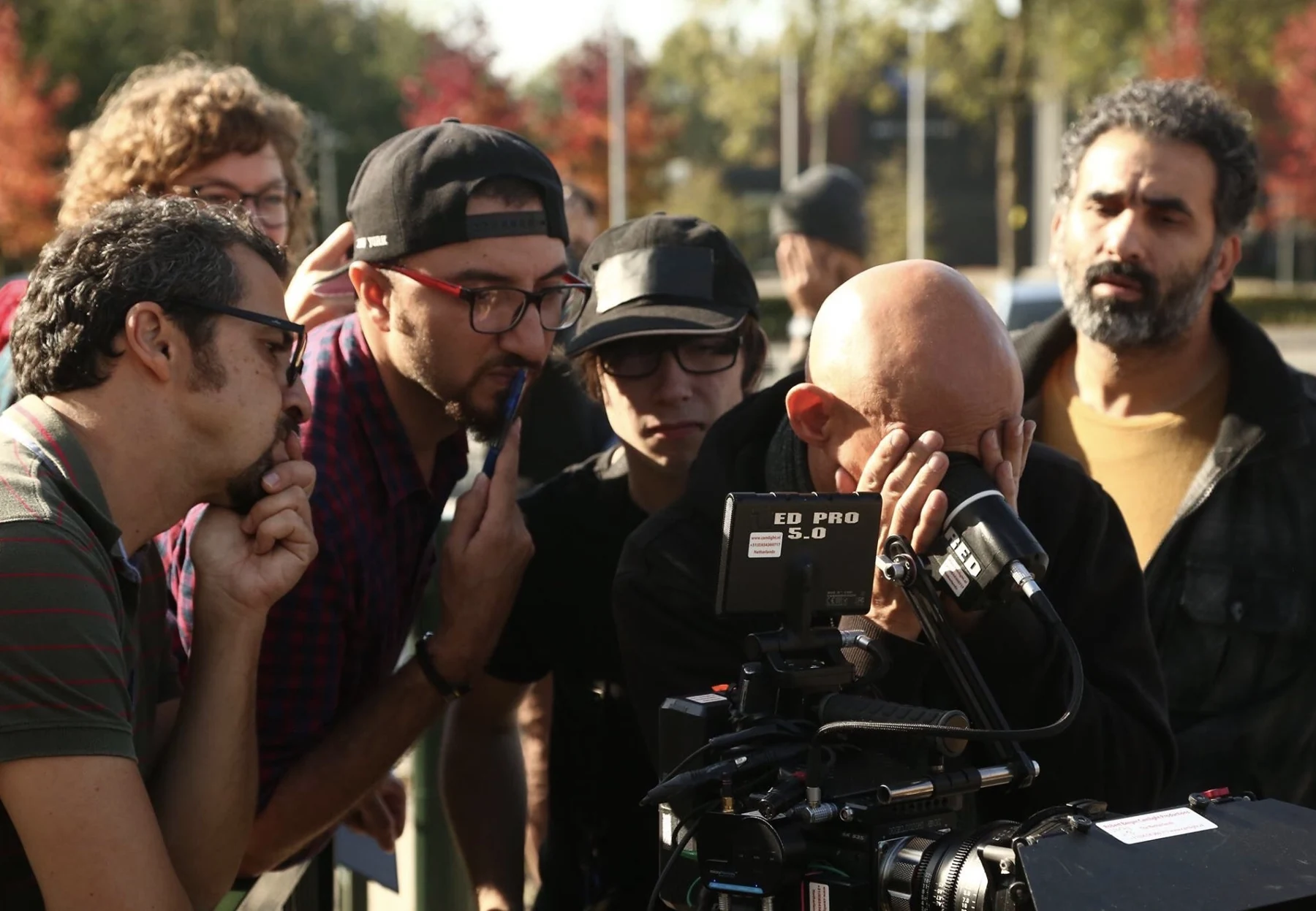 Cyrus Esfandiari on a film set with the crew reviewing a camera shot